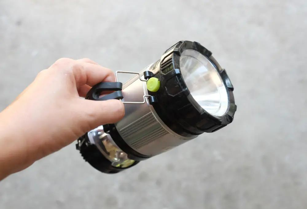 Рука держит раскладной мощный LED-фонарь с ручкой