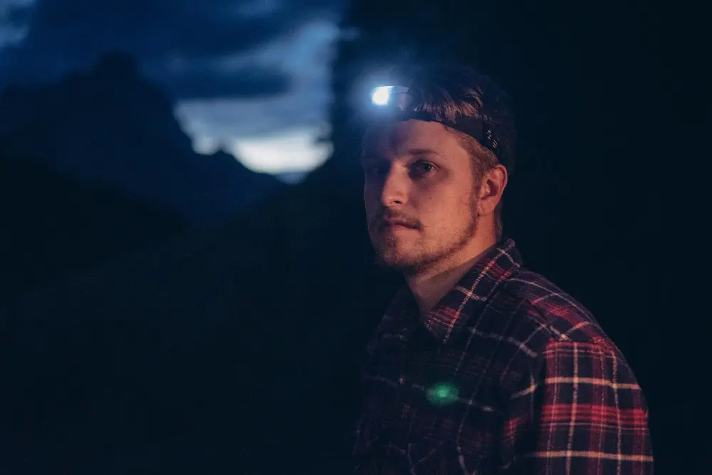 Мужчина в темноте с налобным LED-фонарем - пример выбора hands-free моделей