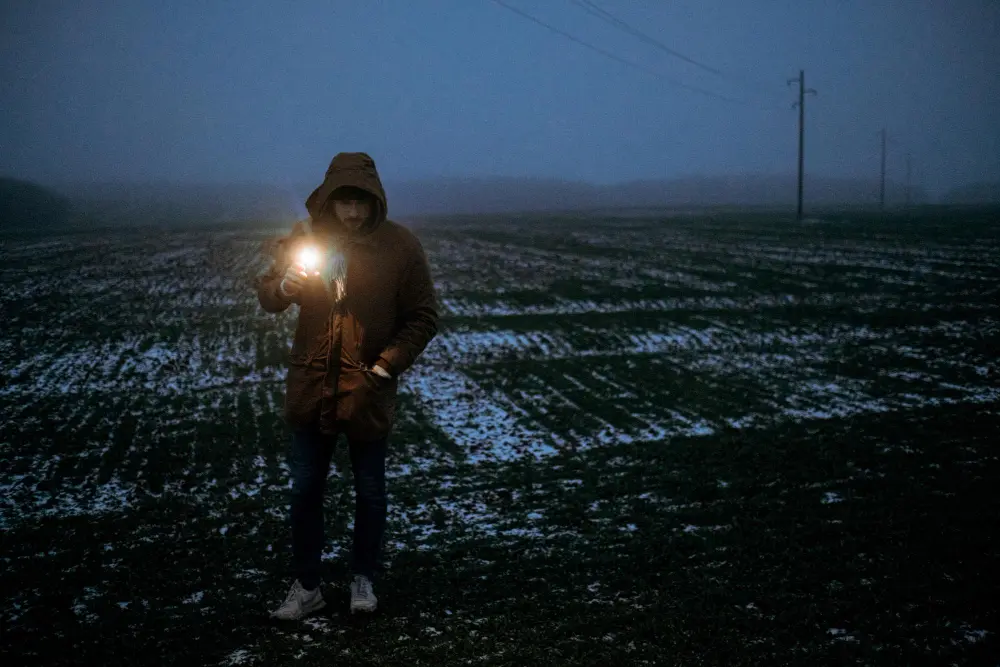 Мужчина в зимнем поле с ручным LED-фонарем в тумане – выбор моделей по типам, дальности и автономности