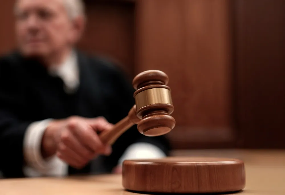 Суддя з молотком під час засідання, що символізує винесення судового рішення про незаконність звільнення працівника на підставі відеозапису та визнання відеонагляду інструментом мобінгу або тиску.